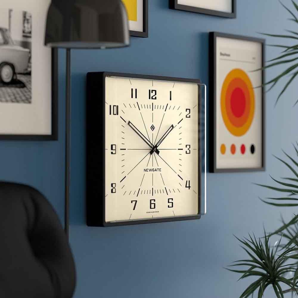 Horloge murale moderne du milieu du siècle dernier Box office, signée Newgate, avec un cadran rétro. Le boîtier rectangulaire est fini en silicone noir mat et contient une lentille en acrylique moulé qui dépasse du cadran vers l'avant.