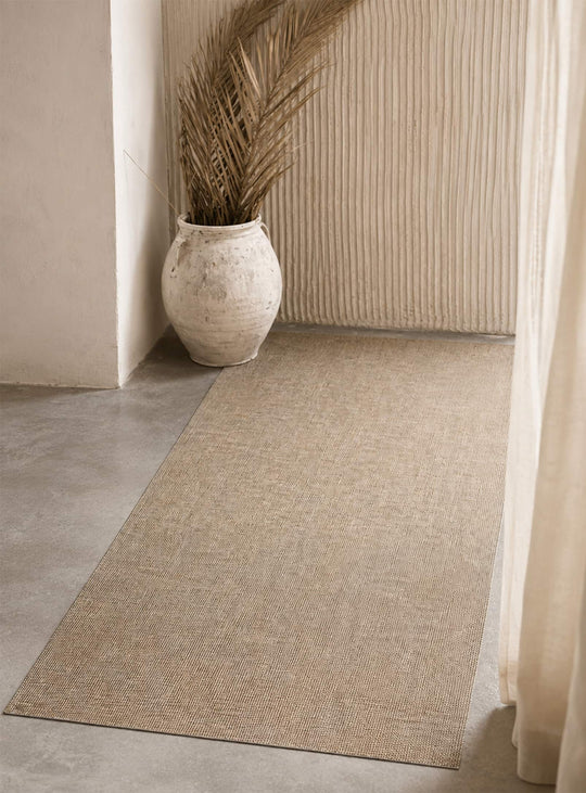 Tapis Casau d'Adama Alma, en vinyle brun au motif texturé inspiré du tissage naturel pour un décor chaleureux.