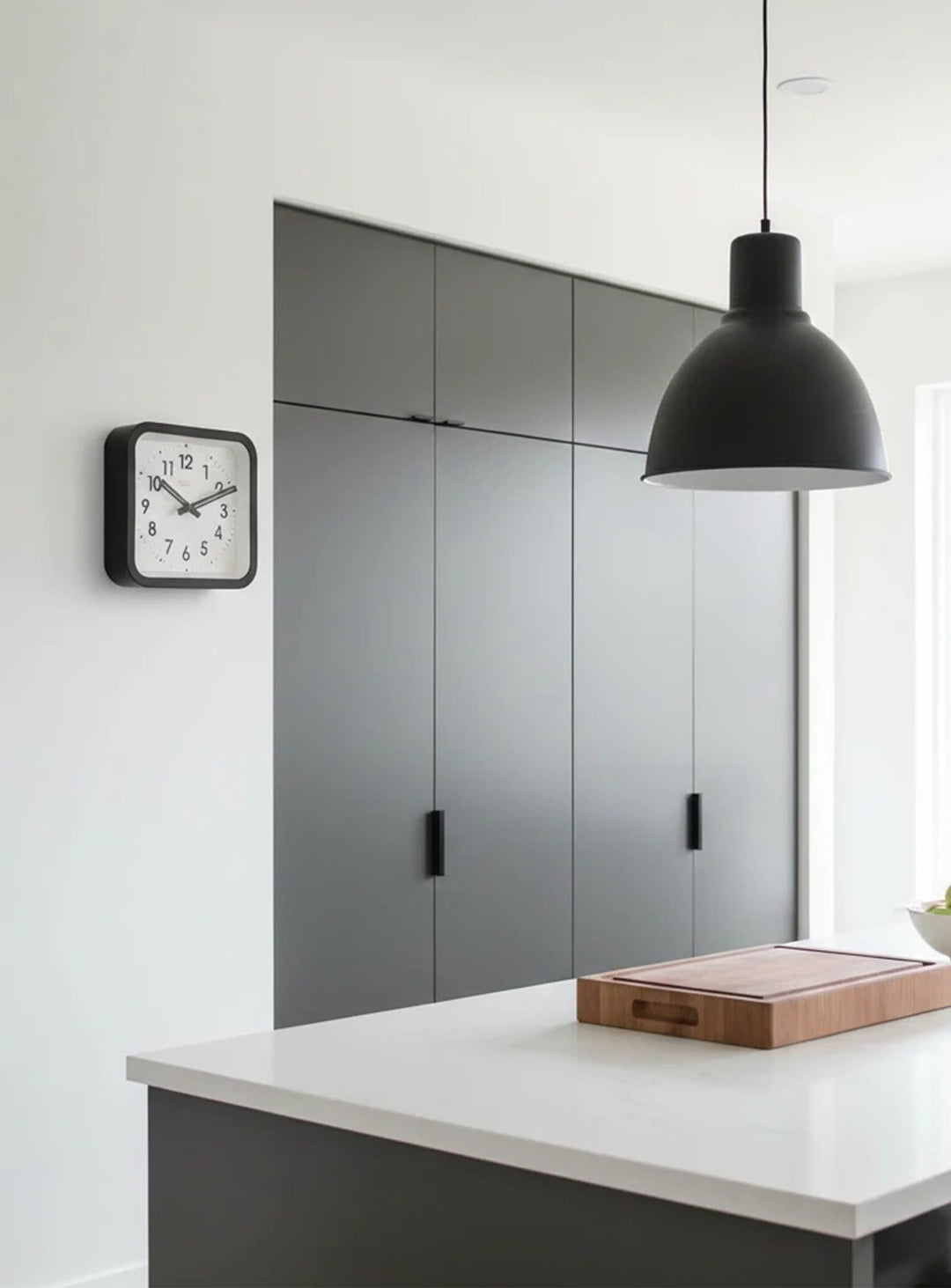 Horloge Cloudnola Square : un modèle 36 cm élégant avec mouvement silencieux et aiguilles visibles dans la pénombre.