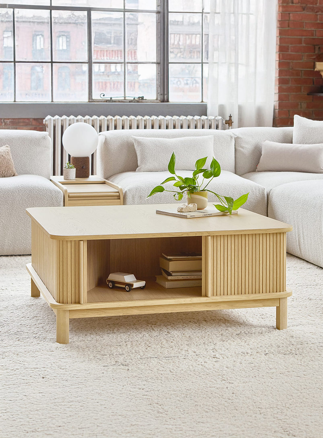 Table à café Ledger de Gus* : un meuble élégant en bois FSC® avec portes tambour glissantes sans quincaillerie visible.