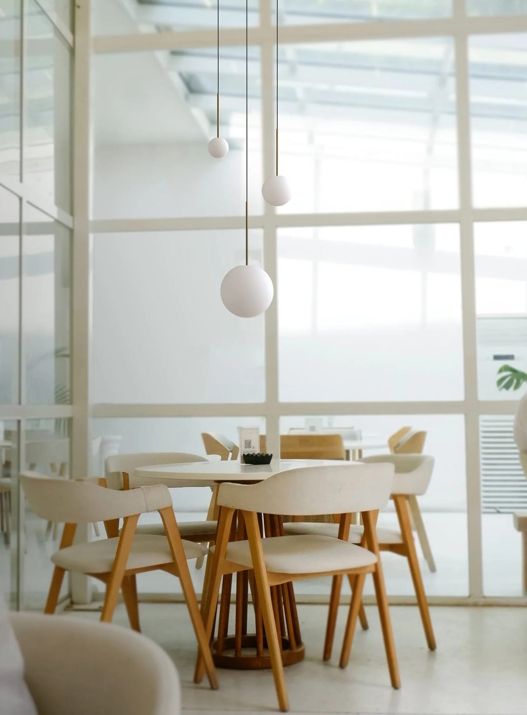 La lampe suspendue Bola Sphere de Pablo Designs allie finesse de l'acier inoxydable et élégance du verre opale. laiton