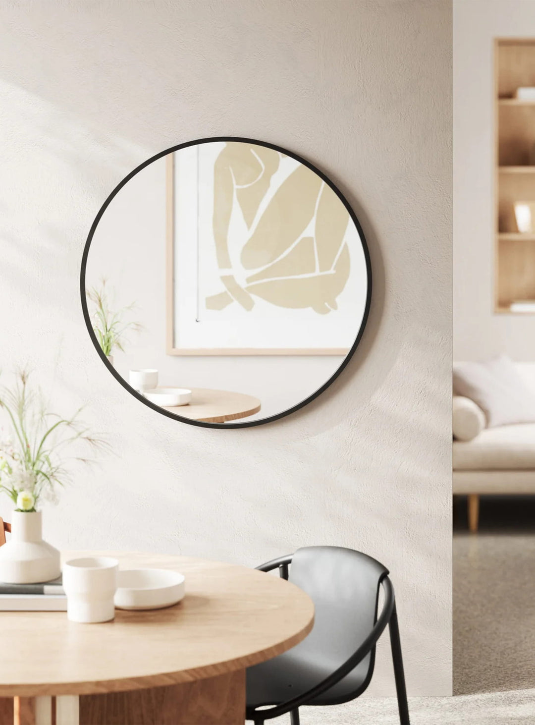 Le miroir mural Hub d'Umbra combine forme ronde, cadre noir et design contemporain pour agrandir visuellement l'espace.