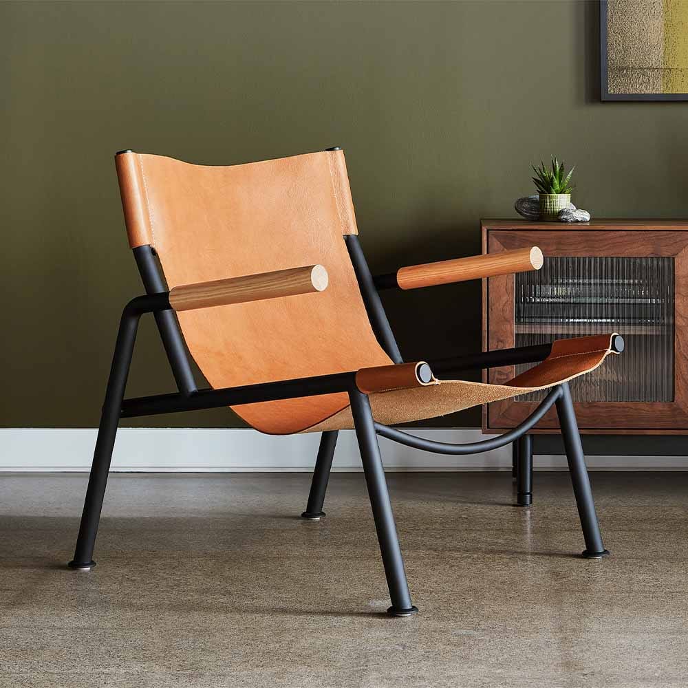 La chaise lounge Wyatt de Gus* Modern : un design de haut niveau qui marie matériaux bruts et élégance. Métal noir, bois massif et cuir tanné végétal pour une expérience de relaxation exceptionnelle.