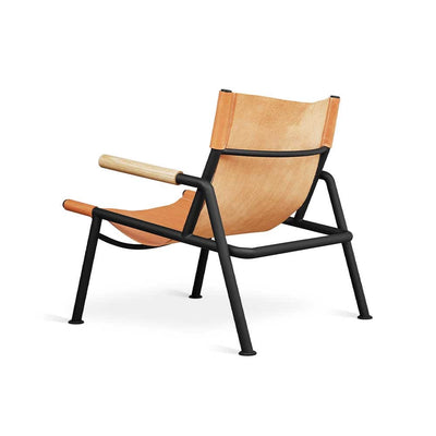 Plongez dans le confort de la chaise lounge Wyatt de Gus* Modern. Structure en métal noir, accoudoirs en bois massif et sangle en cuir tanné végétal pour une expérience exceptionnelle.