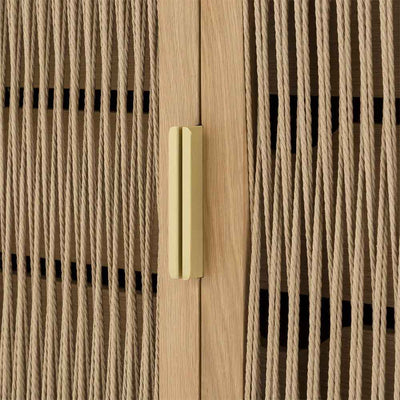 Découvrez la commode Lumina : un meuble qui marie originalité et élégance. Le bois, les portes à la corde et les poignées en laiton en font un élément de décoration distinctif.
