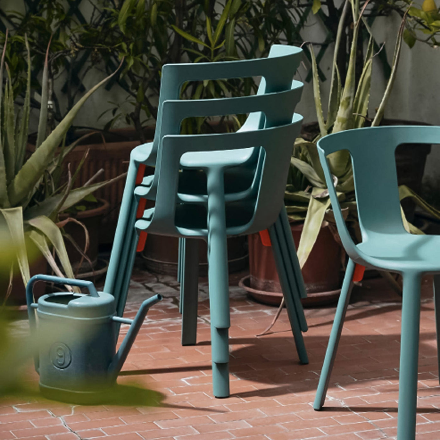 La chaise FLA de TOOU offre un mariage harmonieux entre légèreté et adaptabilité, avec des ailettes orange vif soulignant sa capacité d'empilage jusqu'à six chaises pour un stockage pratique.
