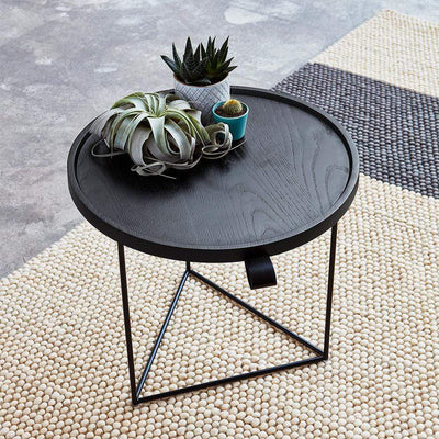 La table d'apppoint Porter de Gus* modern est un meuble d'appoint fonctionnel et organique doté d'un plateau roulé en noyer massif, qui repose sur un cadre métallique triangulaire et élégant.