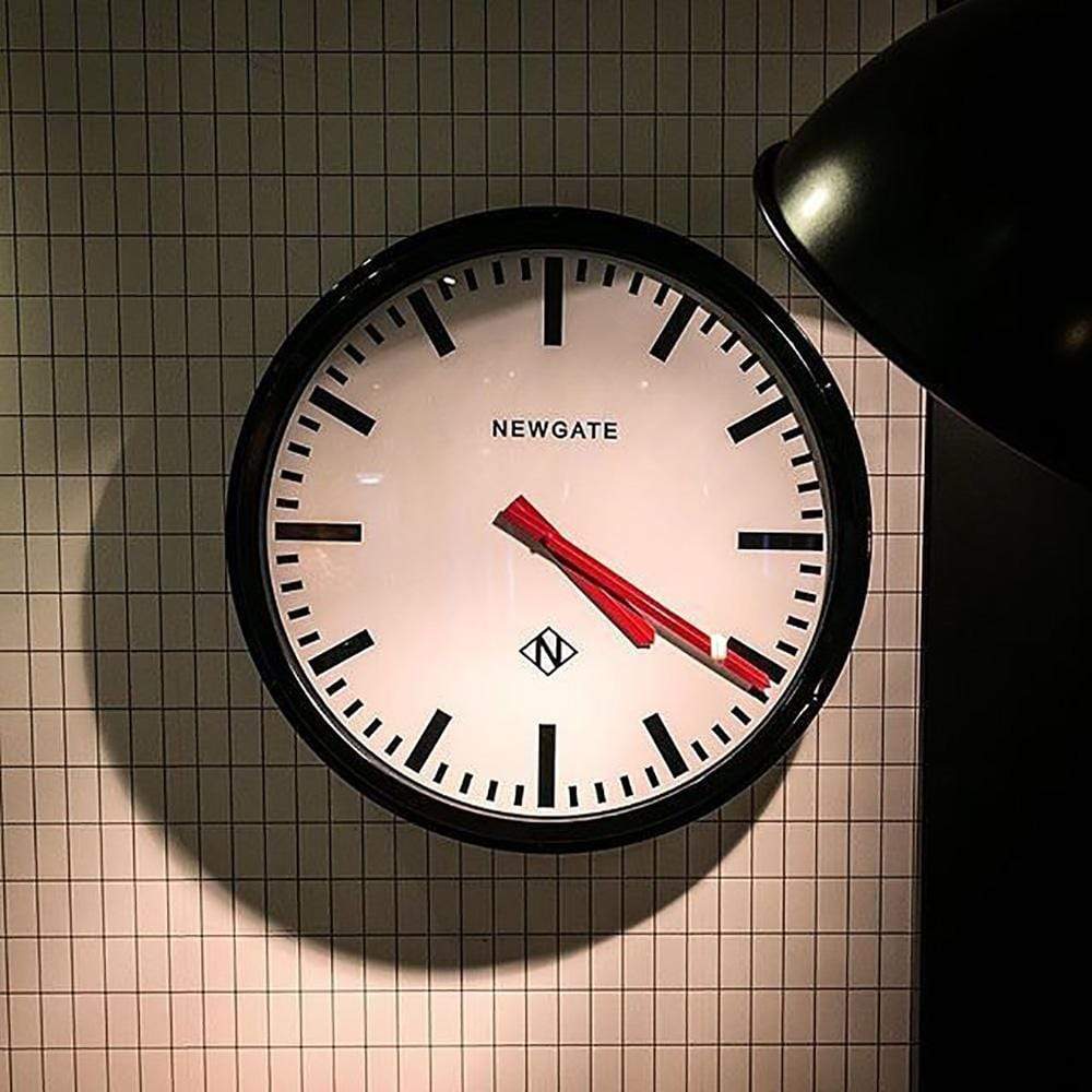 Metropolitan par Newgate est une horloge industrielle surdimensionnée, avec un boîtier en métal peint en noir, une lentille en verre et des aiguilles en métal rouge, qui se place dans n'importe quel environnement, dans l'entrée, la cuisine ou le bureau.