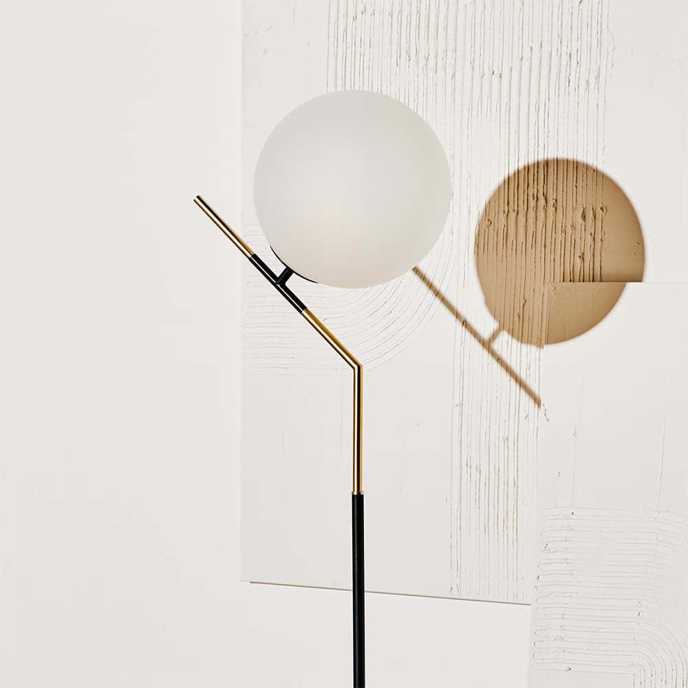 Lampe Declan : une œuvre d'art évoquant le raffinement des lampadaires des années 20, avec sa tige courbée et son globe en verre blanc.