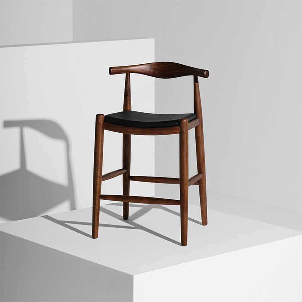 Avec son coussin d'assise en cuir moulé et son bois massif sculpté, le tabouret Maja offre confort et sophistication dans un design discret.