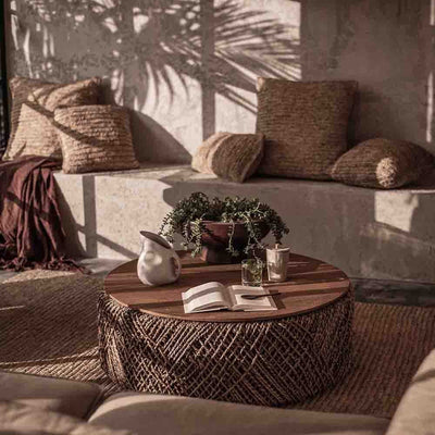 Knut, une table à café écologique et raffinée. Base tissée à la main en abaca durable, plateau en teck recyclé aux motifs narratifs. Un charme artisanal avec une fonctionnalité discrète.