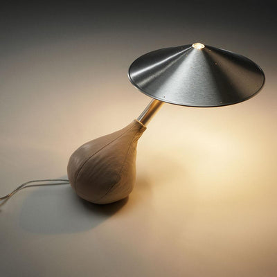 Un cuir italien souple recouvre la base flexible de la lampe Piccola de Pablo Designs, qu'un utilisateur peut incliner à n'importe quel angle tandis que son abat-jour en aluminium flotte pour rester à niveau.